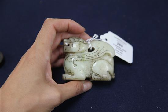 A Chinese pale celadon and black jade recumbent figure of a winged mythical beast, length 7cm, wood stand, some black staining to the s